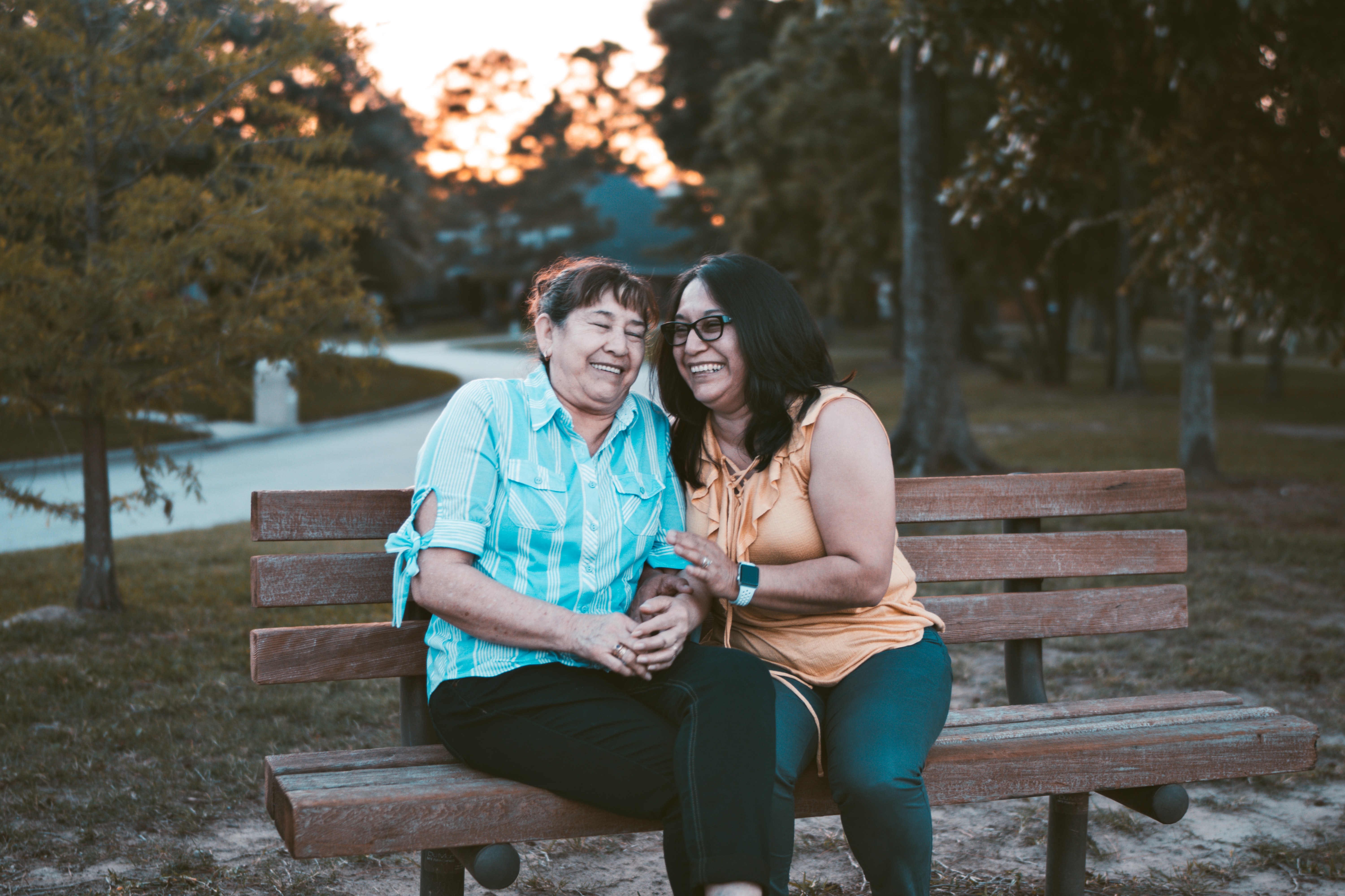 Two people laughing while sitting on a bench outside